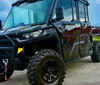 The image shows a rugged black all-terrain vehicle with large tires parked outdoors with a small inset showing an alternate view