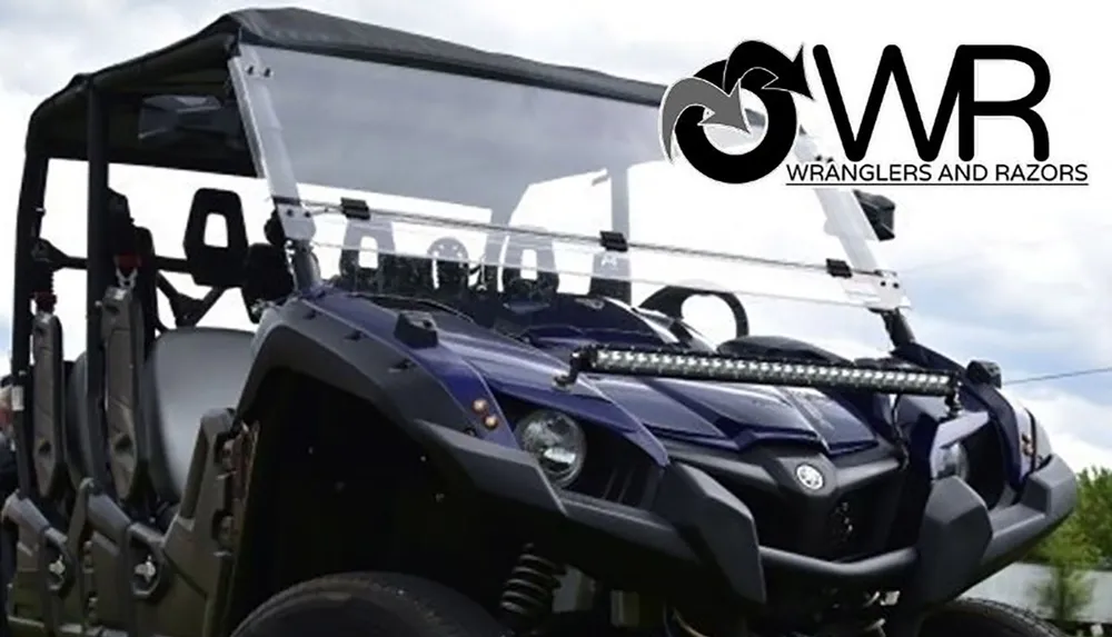 A rugged off-road vehicle with a clear windshield and a mounted light bar is shown featuring the Wranglers and Razors logo in the corner