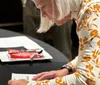 A woman holds up a drawing on a whiteboard during a lively dinner show alongside positive testimonials and an inset of a pasta dish