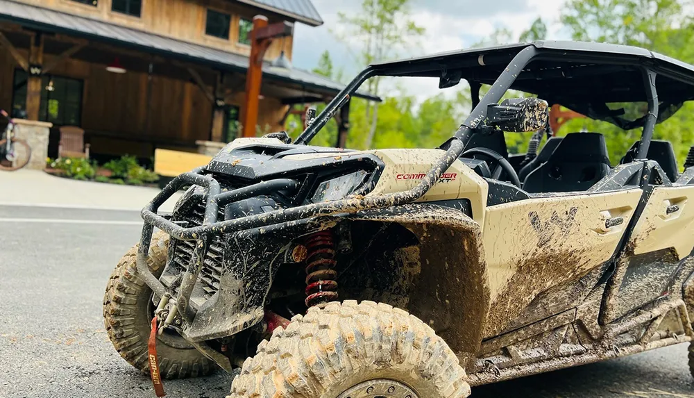 A muddy off-road vehicle parked on a street in front of a wooden building