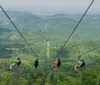 A person wearing a helmet and harness is zip-lining over a vast scenic landscape
