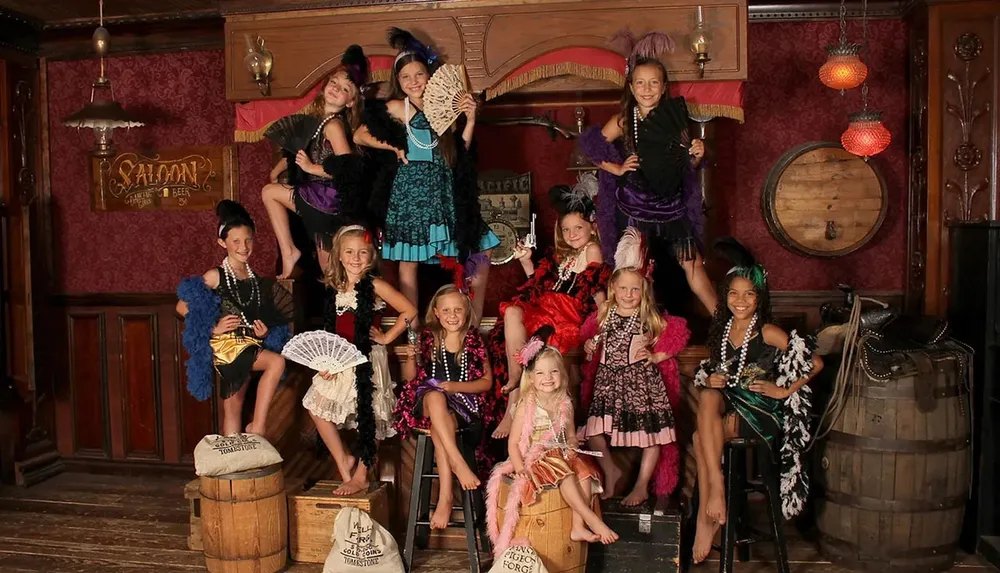 A group of girls dressed in vintage saloon-style costumes pose together in an Old West-themed setting