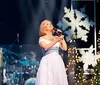 The image showcases a vibrant stage performance at a Christmas-themed Country Tonite show featuring singing dancing and violin playing under festive decorations