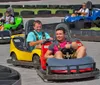 Two children are enjoying themselves while driving go-karts on a track lined with tires