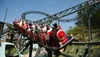A group of excited people are riding a roller coaster with a red front car that resembles a classic steam engine.