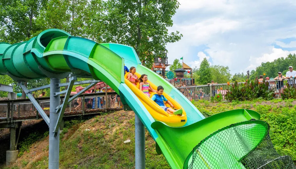 A group of people are sliding down a colorful water slide in an amusement park on a sunny day