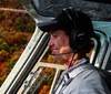 Two adults and a child are wearing headphones while enjoying a scenic helicopter flight