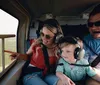 Two adults and a child are wearing headphones while enjoying a scenic helicopter flight