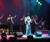 A group of performers are singing on stage under colorful stage lighting