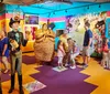 A child interacts with an interactive exhibit at a space-themed attraction while another childs face is humorously positioned in the helmet of a large astronaut statue