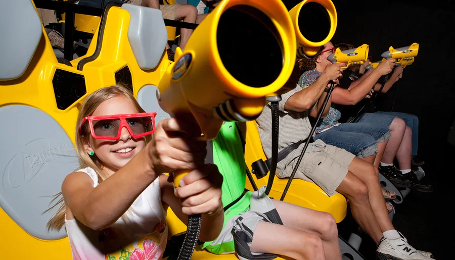 People are enjoying an interactive 3D ride, wearing glasses and using handheld devices to aim at targets.