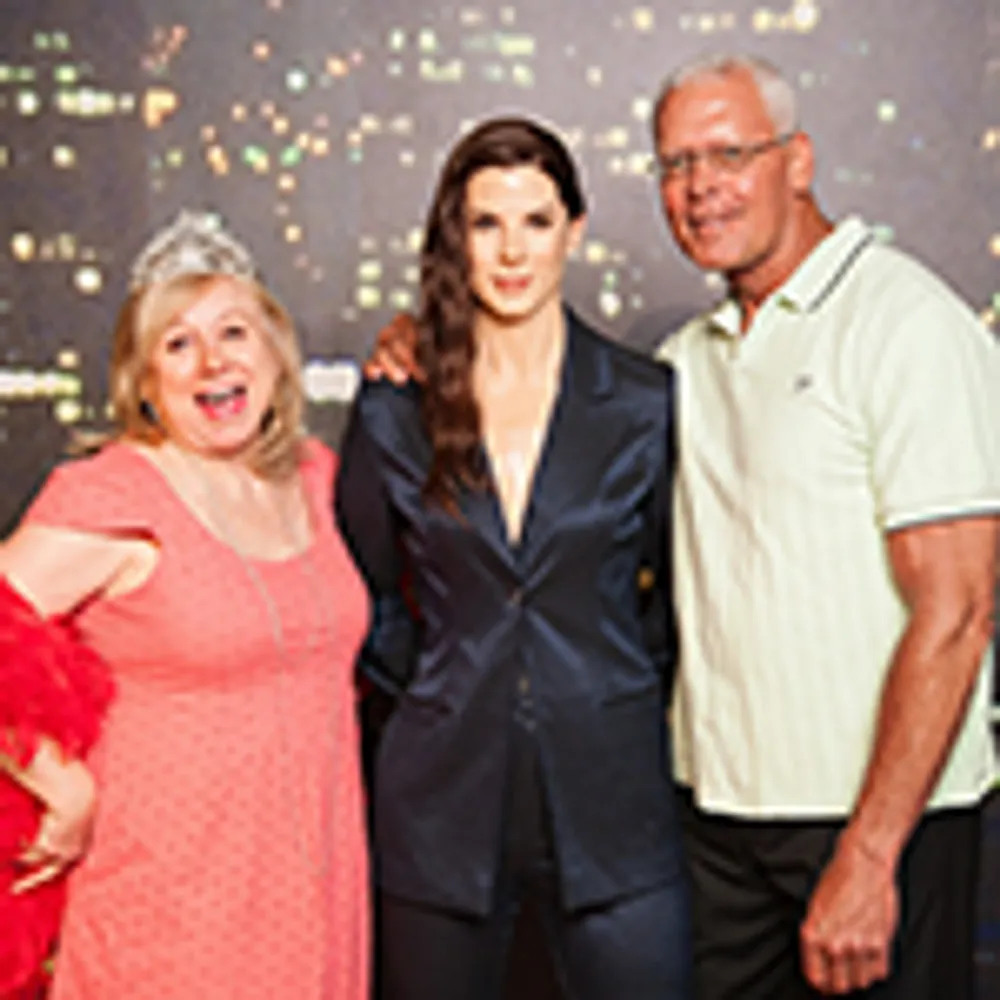 Three people are posing together with one wearing a tiara and the others dressed more formally