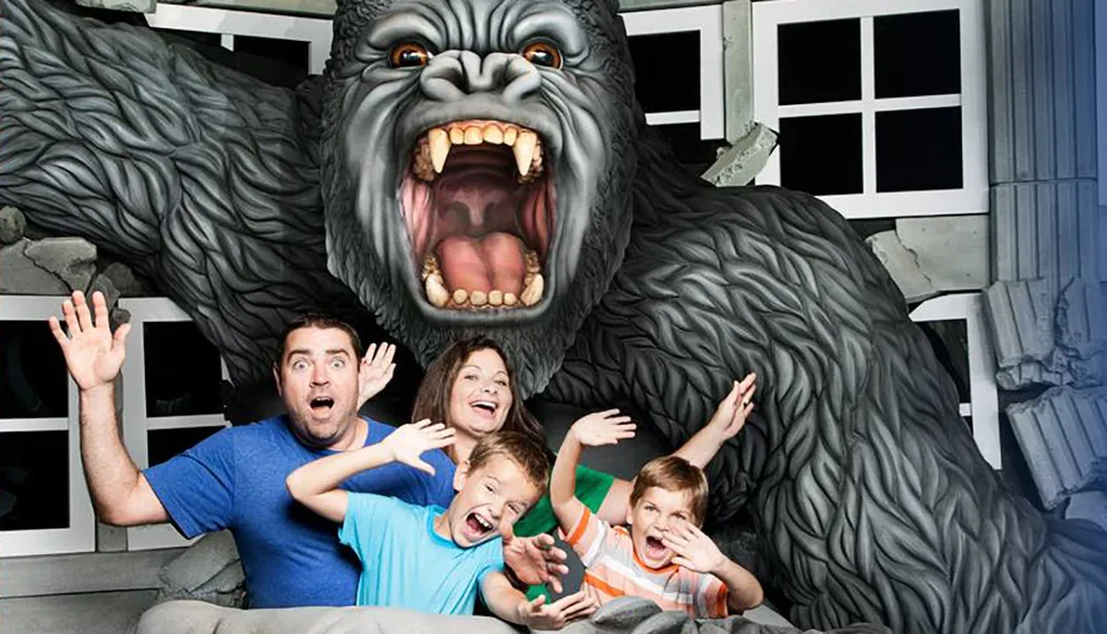 A family is posing with exaggerated expressions of fear as if they are being attacked by a large gorilla in what looks to be a staged amusement park photo opportunity