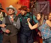 A group of performers in Western attire are animatedly acting on stage with an inset image showing a variety of hearty Southern-style foods on a table