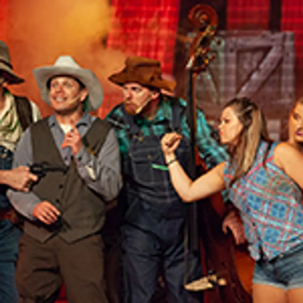 A group of people in cowboy and rural costumes are acting energetically on stage one holding a gun and another holding a double bass