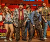 The image shows a lively group of performers on stage likely from a Hatfield  McCoy-themed dinner show with some playing musical instruments and others singing or acting evoking a sense of fun and entertainment