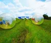 Three individuals are enjoying themselves while navigating through water inside a transparent inflatable zorb ball