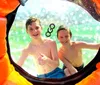 Three individuals are enjoying themselves while navigating through water inside a transparent inflatable zorb ball