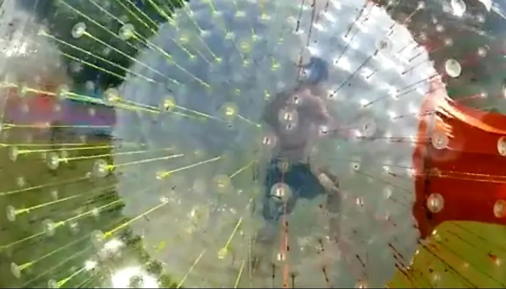 This image appears to show a person inside a transparent sphere likely a zorb ball which is used for the adventure activity known as zorbing