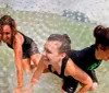 Three individuals are enjoying themselves while navigating through water inside a transparent inflatable zorb ball