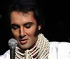 A person wearing an Elvis Presley-style costume is holding a microphone presumably performing or about to perform