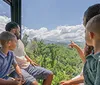 A family is enjoying a scenic view from inside a cable car ride surrounded by lush green forests under a blue sky