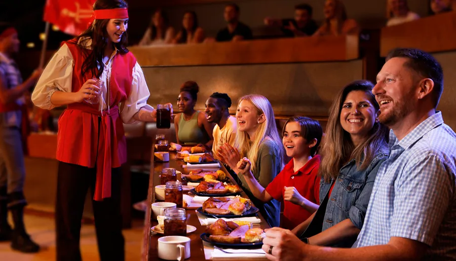 A group of people enjoys a themed dining experience, with a server dressed as a pirate offering drinks.