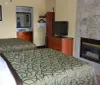 This image shows a neatly maintained hotel room with two queen-size beds patterned bedspreads and basic amenities