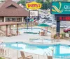 The image shows a hotel complex featuring Quality Inn  Suites with an outdoor swimming pool area a Dennys diner in the background and a parking lot with several cars