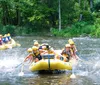 A group of people wearing life jackets and helmets are joyfully white water rafting splashing through a rapid