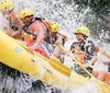 A group of people wearing life jackets and helmets are joyfully white water rafting splashing through a rapid