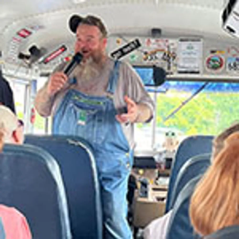 A person in overalls is speaking into a microphone on a bus