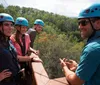 Three people are enjoying a zip-line adventure through a forested area with two of them actively gliding down the line while another waits on a platform