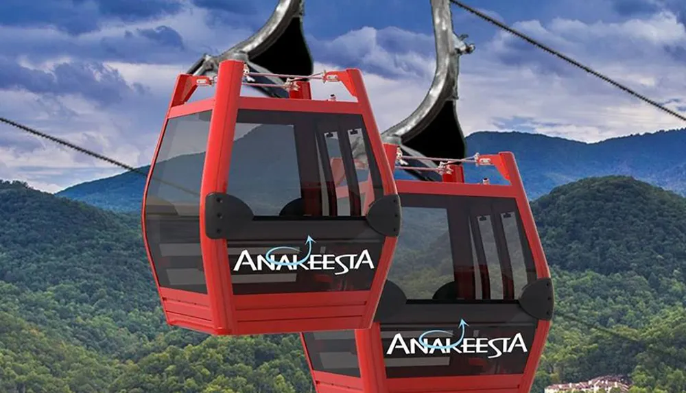 The image shows two red cable cars with Anakeesta written on them set against a backdrop of mountainous terrain