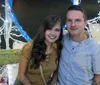 A smiling couple is sitting inside an ornate light-adorned carriage at night