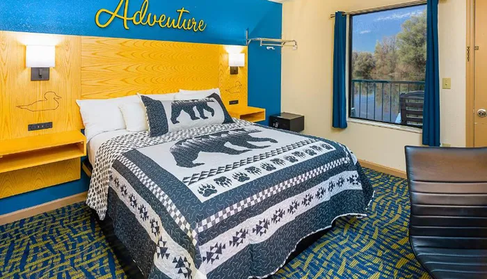 This is a themed hotel room with an Adventure motif featuring a bear patterned bedspread wildlife silhouettes and a nature-inspired color scheme