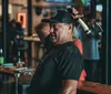 A man is holding an axe over his shoulder with a playful expression likely at an axe-throwing venue or similar social setting