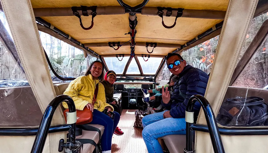 A group of people is sitting inside an open-sided vehicle, enjoying a ride together.