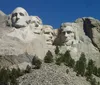 This image shows a crowd of visitors gazing at the iconic Mount Rushmore National Memorial under a clear blue sky