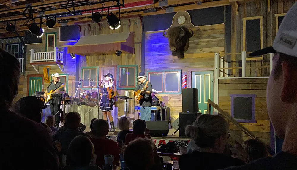 A band performs on a stage adorned with rustic decor and a mounted bison head entertaining an audience in a venue with a Western theme