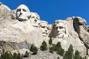 The image shows the iconic Mount Rushmore National Memorial, featuring the carved granite faces of four former U.S. presidents.