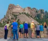 Tourists are gathered at an observation area to view the Mount Rushmore National Memorial which features the carved faces of four US presidents