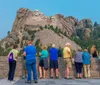 Tourists are gathered at an observation area to view the Mount Rushmore National Memorial which features the carved faces of four US presidents