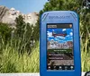 Three smiling women are using audio guide devices likely on an outdoor tour