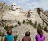 Three children are gazing at the monumental sculpture of four US presidents carved into Mount Rushmore