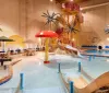 The image features an indoor water park with a pirate ship-themed play structure a waterslide and several seating areas under umbrellas