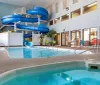 The image shows an indoor swimming pool area with a waterslide and a hot tub within a hotel or leisure complex