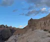 A couple is posing for a photo with a backdrop of rugged eroded rock formations under a bright sky