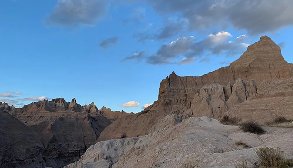 The image showcases a rugged eroded landscape with distinctive rock formations under a cloudy sky