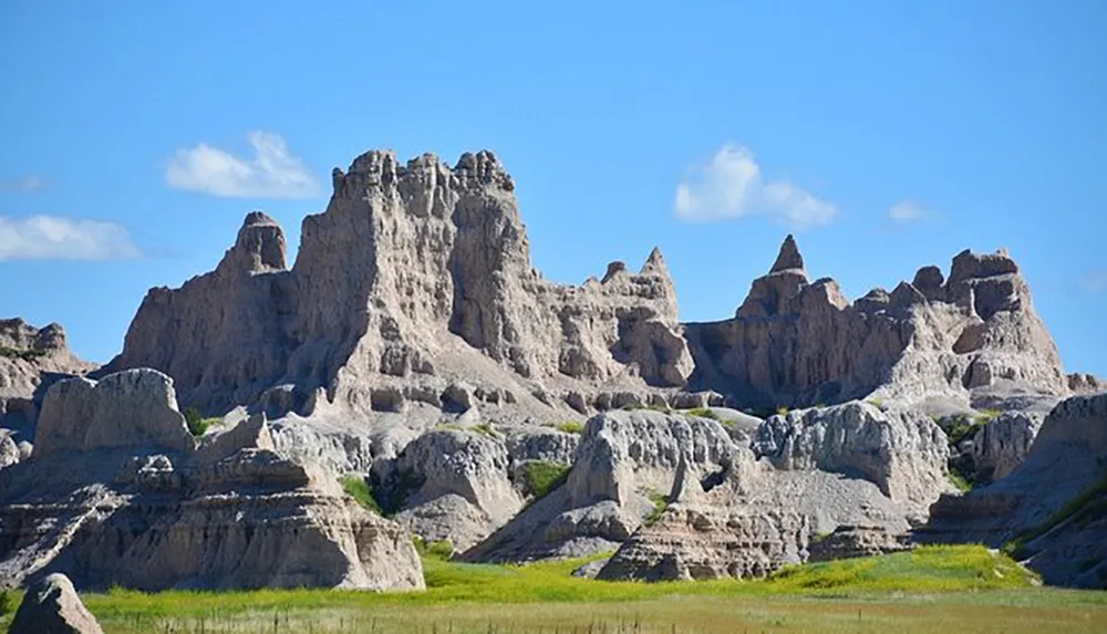 The image shows a rugged landscape with dramatic rock formations and spires under a blue sky suggesting a desert or Badlands region